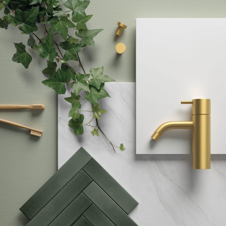 Ett grönt badrum med detaljer i mässing och guld