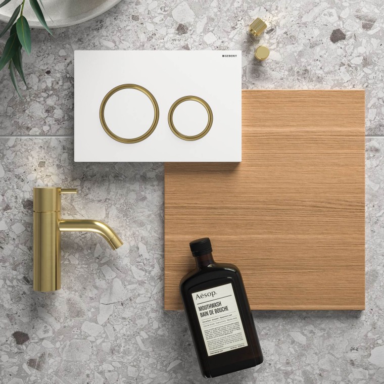 Ett grått badrum med detaljer i mässing och trä